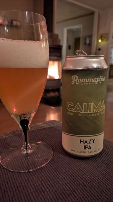 En ölburk med texten "Remmarlöv Calima Hazy IPA" står bredvid ett glas med skummande öl i ett varmt ljus.