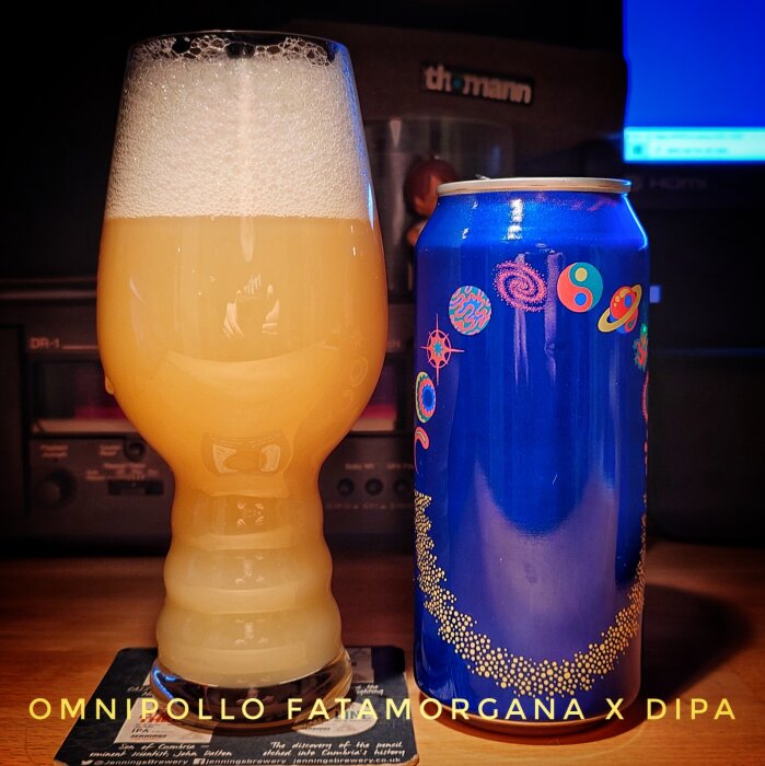 Ett glas grumlig öl bredvid en blå burk med färgglad design, märkt "Omnipollo Fatamorgana x DIPA".