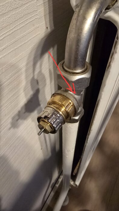 Radiatorventil av typen Danfoss RAV med en röd pil som pekar på kopplingen.