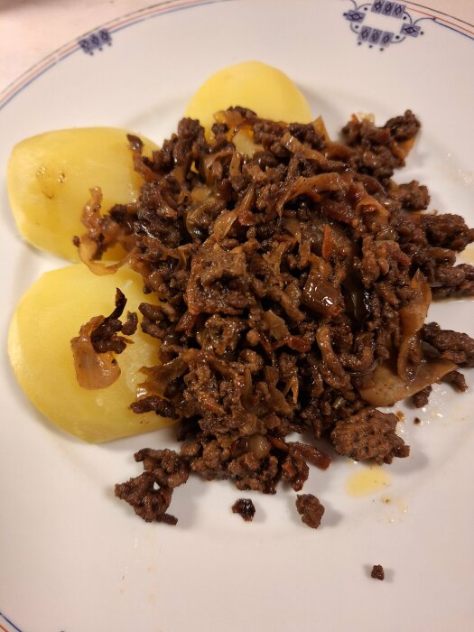 Kål- och färspanna serverad med potatis på en tallrik.