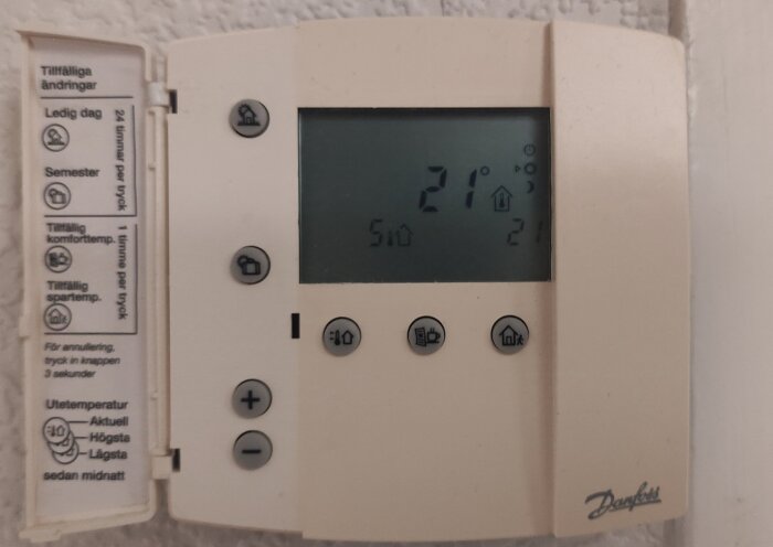 Digital termostatpanel med flera knappar och en display som visar temperaturen 21 grader. Funktionen inkluderar tillfälliga inställningar och justeringar.