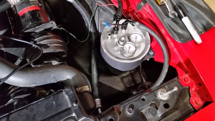 EFI-bränsleinsprutningssystem i motorrum med mätare och slangar, del av diskussion om ersättning från förgasare.