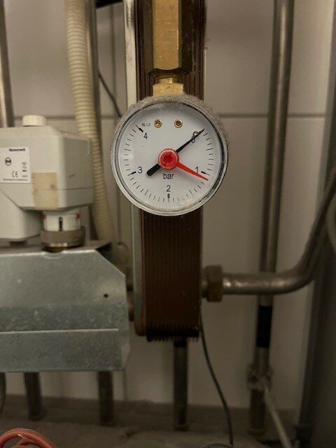 Manometer på fjärrvärmecentral Alfa Laval Cetetherm Mini visar tryck i bar. Rör och komponenter syns runt manometern i värmesystemet.