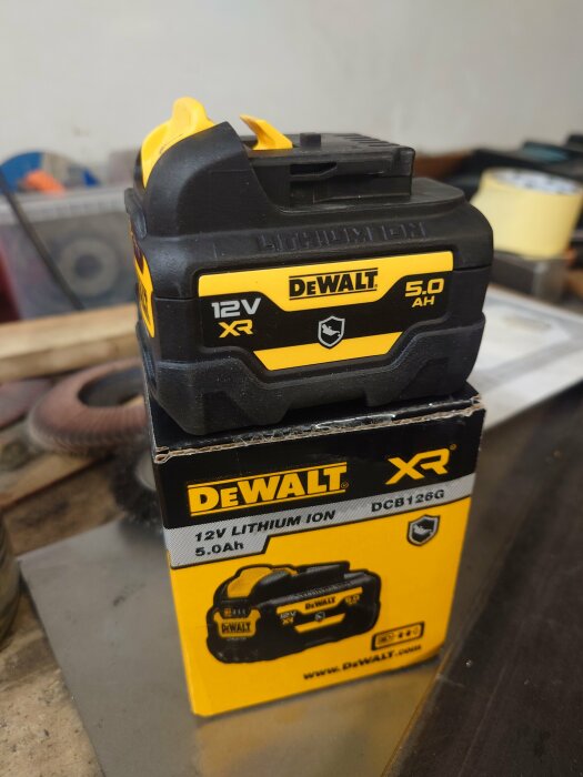 DeWalt 12V XR 5.0Ah lithiumjonbatteri och förpackning på arbetsbänk.