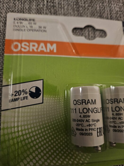 Förpackning med Osram Longlife glimtändare för enkel drift, 4-65W, visas på grön bakgrund med -20% längre lamplivslängd.