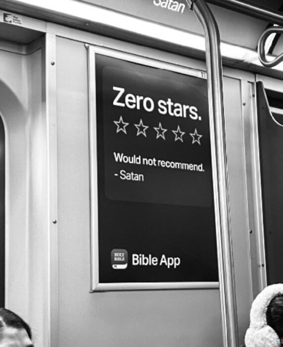 En skylt i ett tåg visar ett betyg på noll stjärnor och texten "Would not recommend. - Satan" med en Bible App-logotyp.