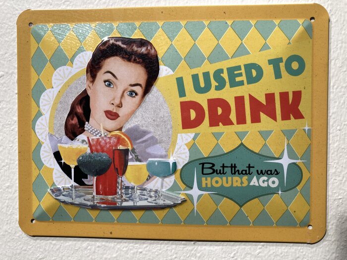 Vintage skylt med texten "I used to drink, but that was hours ago" och bild på en kvinna samt olika färgglada drinkar på ett fat.