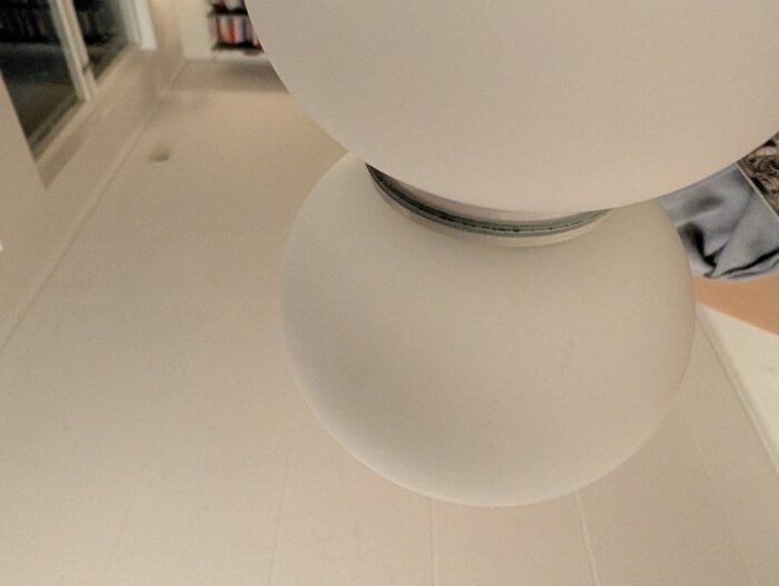 Närbild av en Flos glo-ball cw lampa installerad genom ett hål i väggen. Lampans glas är synligt mot en vit bakgrund.