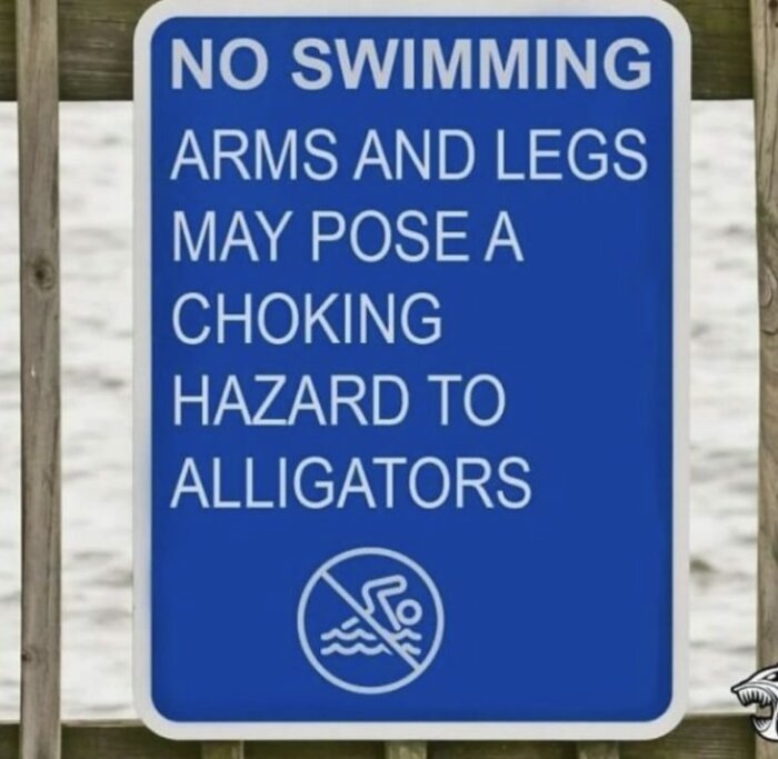 Blå skylt med texten "No swimming. Arms and legs may pose a choking hazard to alligators" och en symbol för förbjuden simning.