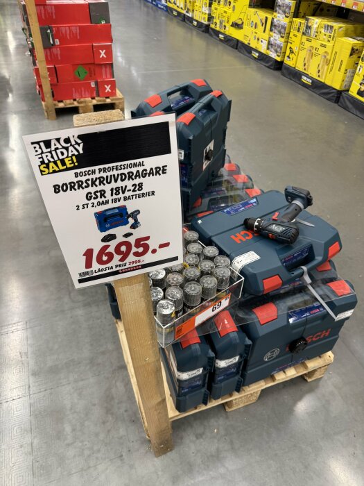 Borrskruvdragare från Bosch på pall med Black Friday-rea, inklusive priserbjudande och förpackad i robusta blåa lådor i butiksmiljö.