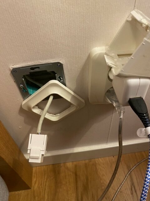 Nätverksuttag av typ Eljo Trend med vinklade uttag och CAT5E-kabel syns på väggen, delvis urmonterat, med intilliggande eluttag.