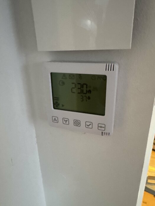 Vit monterad kontrollpanel med display, visar temperatur och symboler. Används som masterenhet och styrs via bluetooth, med betyg på användargränssnittet.