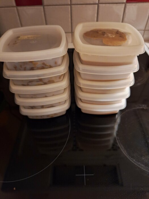 Plastburkar med mat, tvÄ staplar pÄ spishÀllen, fÀrdiga för frysen.