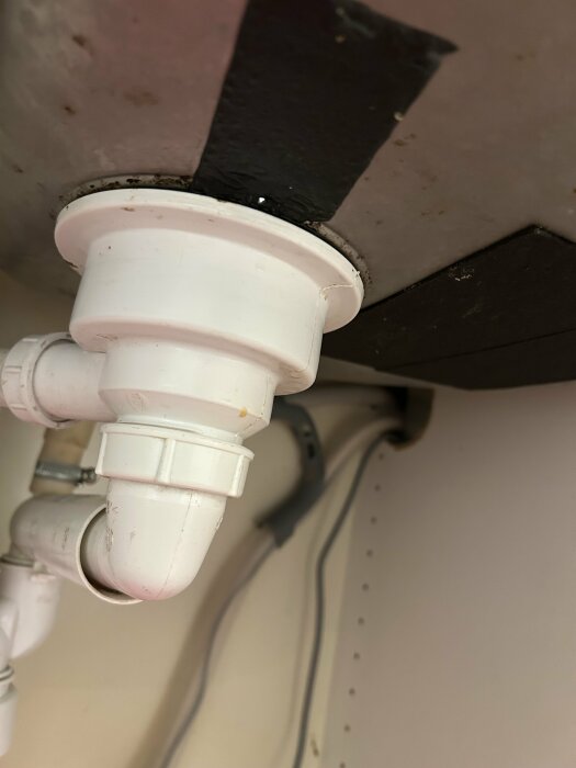 Närbild på rör under diskbänk med lagningstejp där vatten läckt ut.