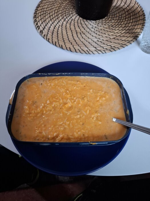 En tallrik med kokt pumpa, ris och mycket grÀdde, garnerad med muskot. En sked vilar i rÀtten.