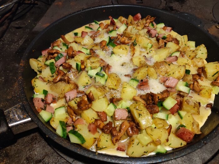 Stekpanna pÄ vedspis med potatis, skogssvamp, zucchini och korv.