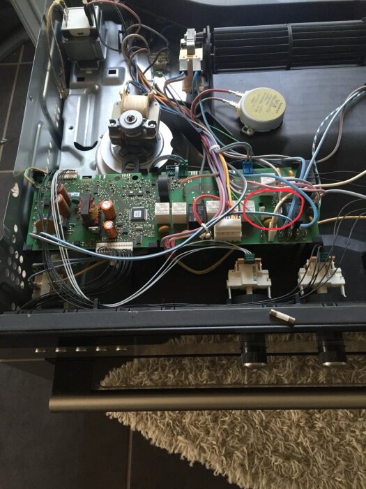 Inre komponenter av en elektronisk enhet, säkringshållaren markerad med röd ring.