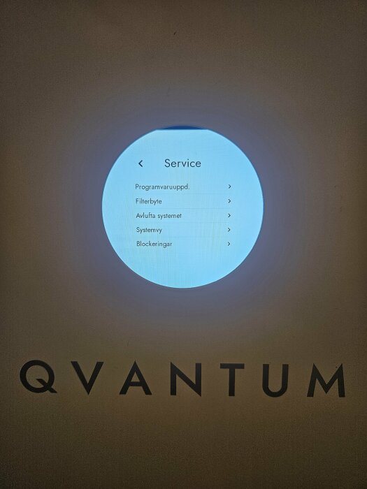 LCD-skärm med servicemeny, inklusive alternativ för programvaruuppdatering och filterbyte. Texten "Qvantum" syns under skärmen.