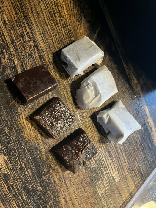 Hemgjord chokladkola med Baileys, några inpackade i papper, på ett träbord.