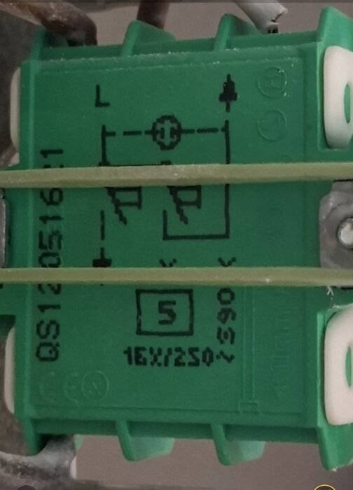 Grön elbrytare med symboler och märkningar, inklusive en streckad linje mellan fas och tändtråd. Etiketter: "QS120516" och "16AX/250V".