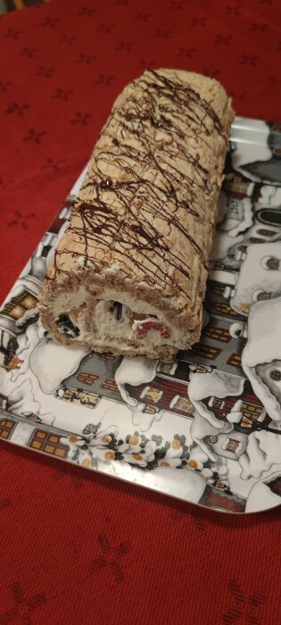 Budapeststubbe med choklad och bärfyllning på ett mönstrat fat, placerad på en röd duk.