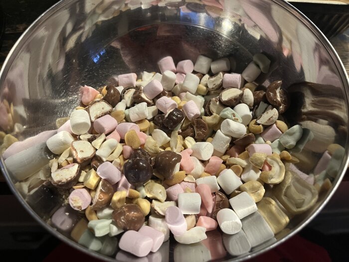 En skål med ingredienser för rocky road: jordnötter, cashewnötter, polly, bilar, minimarshmallows och chokladbitar.