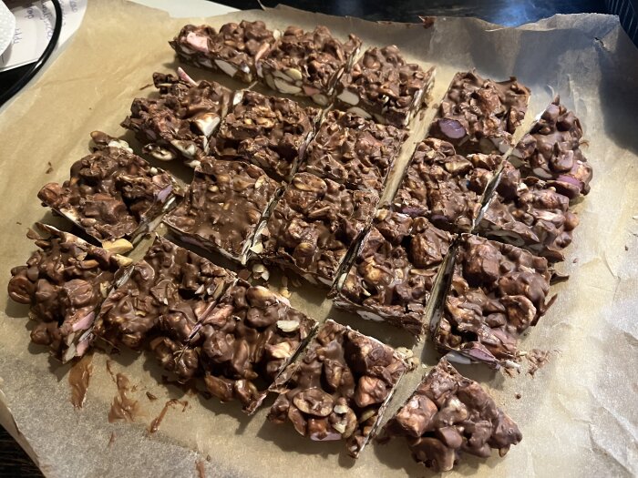 Rocky Road med choklad, polly, bilar, jordnötter, cashewnötter och minimarshmallows skuren i bitar på bakplåtspapper.