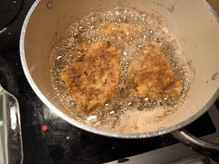 Hemlagad Zinger-kyckling friteras i kastrull på spis, inspirerad av KFC-recept.