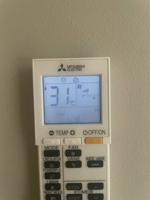 Fjärrkontroll från Mitsubishi Electric visar 31°C, med inställningen "VANE" aktiverad, placerad mot en ljus vägg.