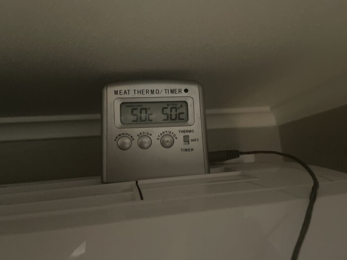En ugnstermometer som visar 50 grader Celsius placerad på en yta, använd för att mäta temperaturen vid ett utblås.