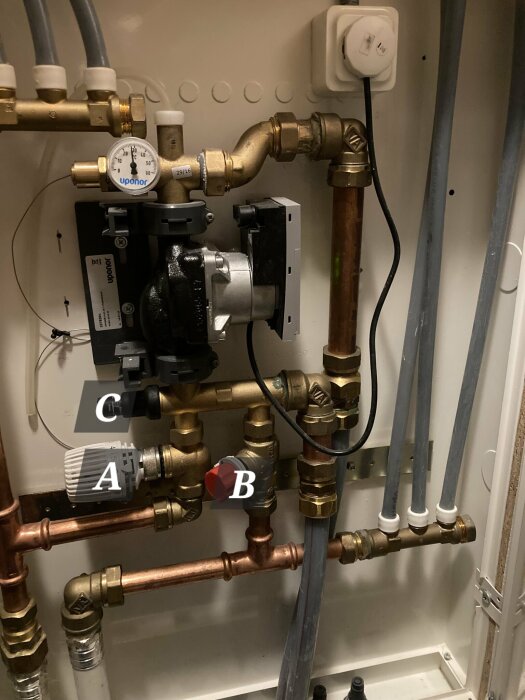 VVS-installation med termostatventil märkt A, röd ventil märkt B och tryckmätare märkt C i rörsystem.