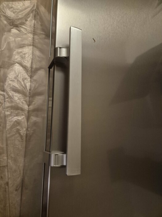 Kylskåpsdörr med handtag på en Electrolux NRE2DE39U 923421420, fokus på gångjärnet och handtagsfästet.