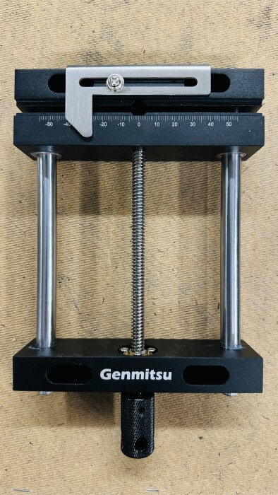 Maskinskruvstycke från Genmitsu, svart metall med justerbara delar, inkl. mätlinjal och gängad stång, placerad mot träbakgrund.