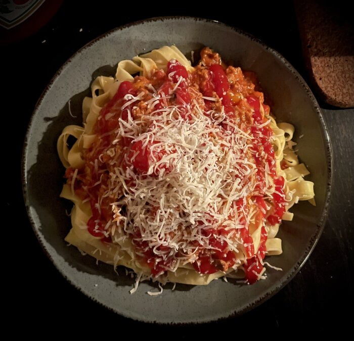 En tallrik med spaghetti, köttfärssås, ketchup och riven parmesanost.