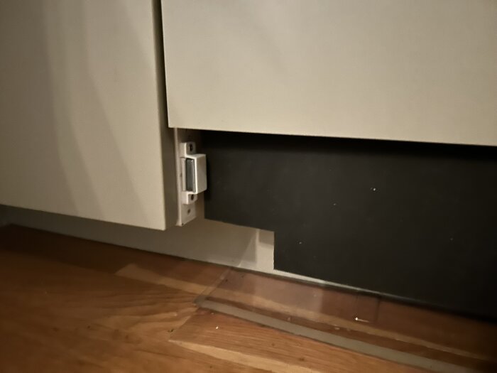 Närbild på kökslucka som har kapats och monterats med magneter istället för vinkeljärn, för att passa en integrerad diskmaskin i IKEA-kök.