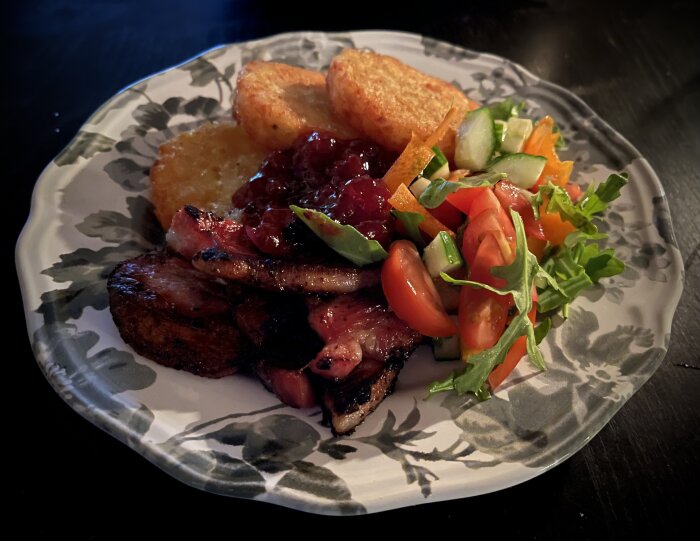 Tallrik med stekfläsk, potatisbullar, sallad och lingonsylt.