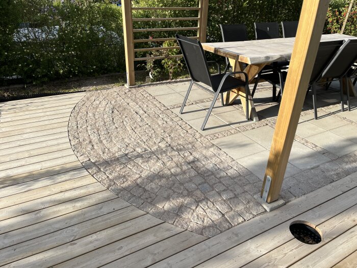 Trädäck med stenlagd yta och matplats under pergola.