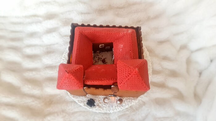 Pepparkakshusmodell av Kuressaare slott, med röda tak och vit bas, dekorerad på en vit bakgrund.