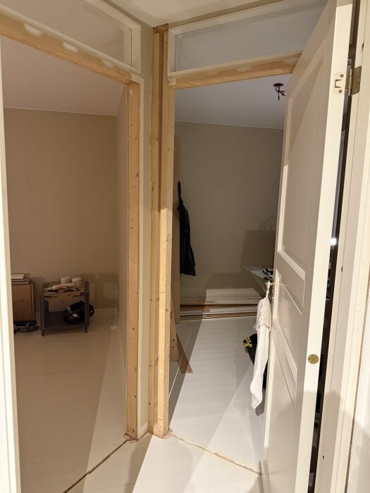 Öppning i hall med två dörrkarmar och oisolerad väggstruktur av trä, pågående renovering med MDF borttaget från väggarna.