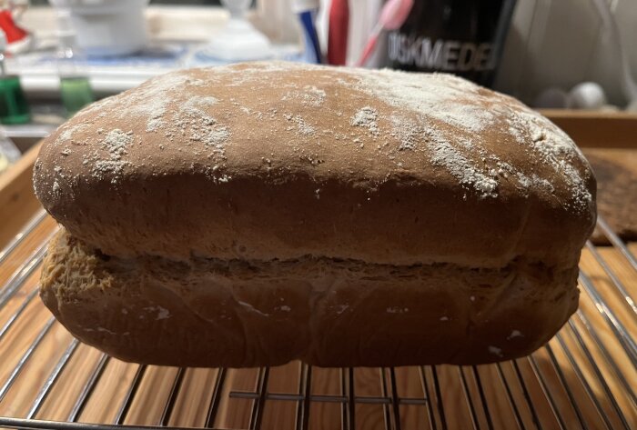 Hemlagad frukostlimpa på ett galler i köket, beströdd med mjöl på ytan.