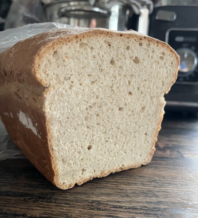 Hemgjord frukostlimpa skuren på mitten, liggandes på en träbänk i ett kök.