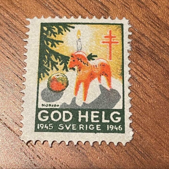 Julfrimärke från Sverige 1945-1946 med en dalahäst, en gran och ett ljus, text "God Helg".