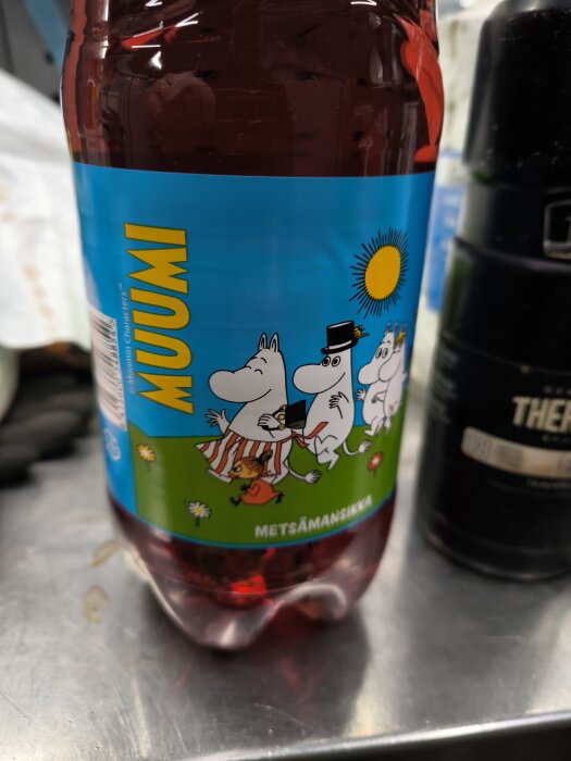 Flaska med Mumin läsk, smak Metsämansikka, på ett metallbord i Hämeenlinna.