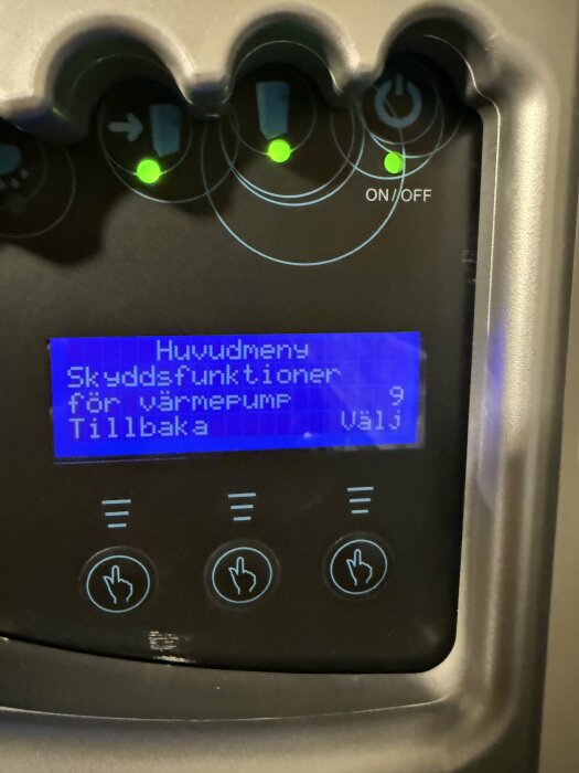 Skärm på Rego637 som visar huvudmenyn med skyddsfunktioner för värmepump, meny 9, och tre tryckknappar nedanför.