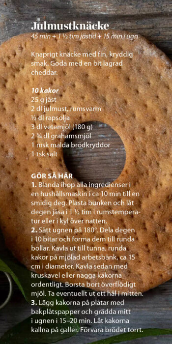 Recept för julmustknäcke med instruktioner och ingredienser, avbildat över ett runda knäckebröd med hål i mitten, liggande på en trätallrik.