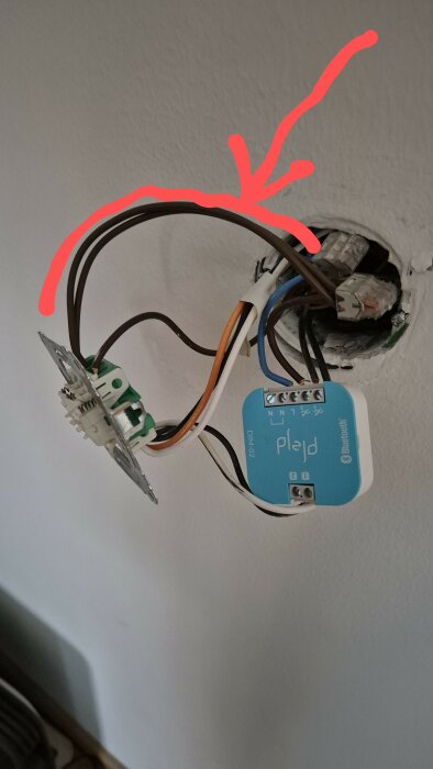 Elektrisk installation med ny dimmer och kablar i eluttag, med en röd pil som pekar på anslutningarna.