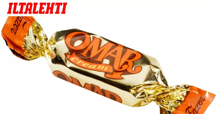Insvept godisbit med texten "OMAR cream" på förpackningen i guldfärg och brunt.