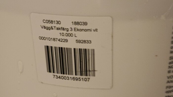 Vit färghinksetikett med texten "Vägg&Takfärg 3 Ekonomi vit 10,000 L" och streckkod synlig.