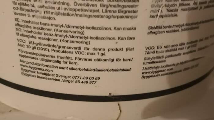 Närbild på etiketten av en gammal målarfärghink, med text som beskriver innehåll och varningar på flera språk.