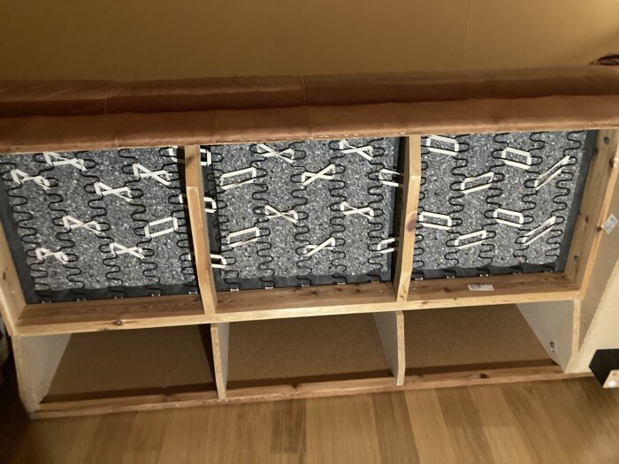 Insidan av en skinnhörnsoffa med hårda skumplastskivor och gummiband över nozagfjädrar, del av en renovering.